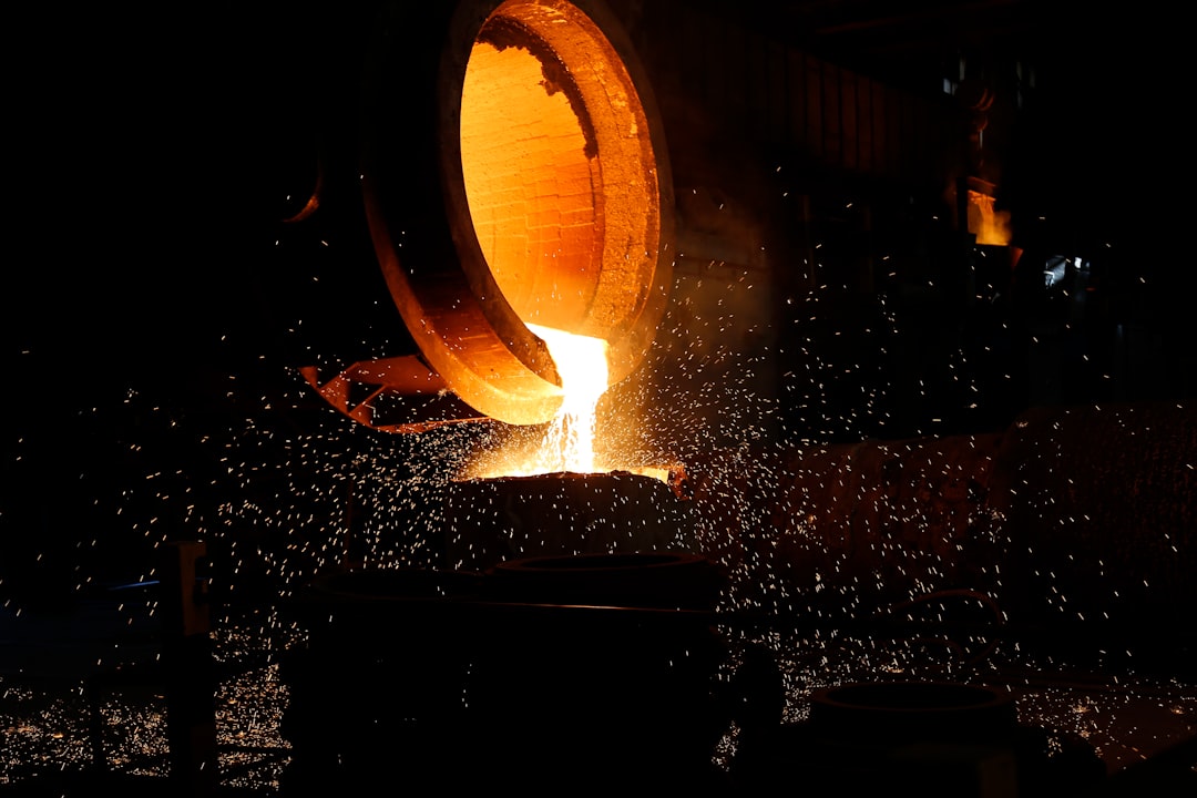 Molten metal pouring from a foundry ladle into a mould, sparks flying